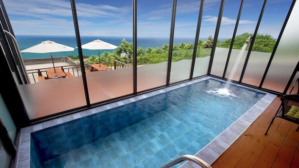 A pool with a clear view of the ocean and greenery. - The Marine Pool Villa (Gyeongju)