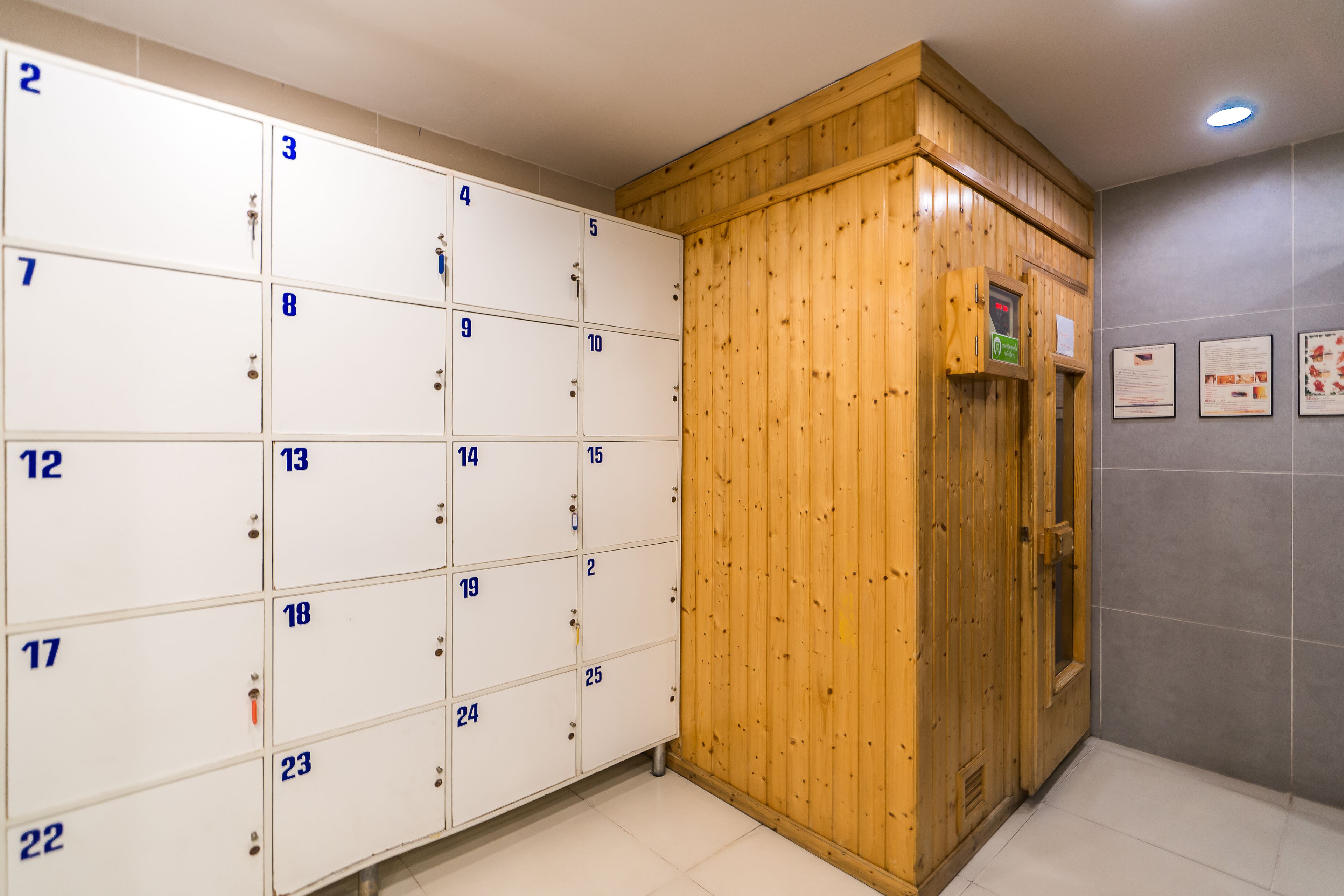 A row of numbered lockers with a wooden cabinet and a wall-mounted information board.