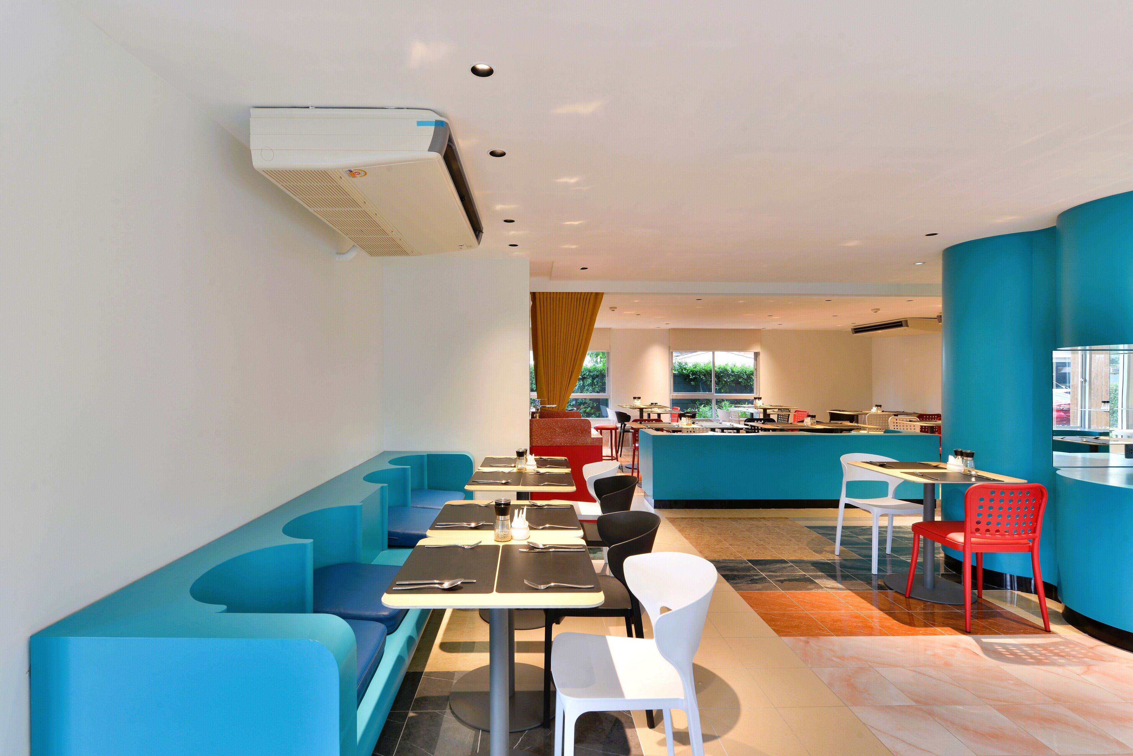 Un restaurant moderne avec des sièges bleus, des tables blanches et un intérieur lumineux.