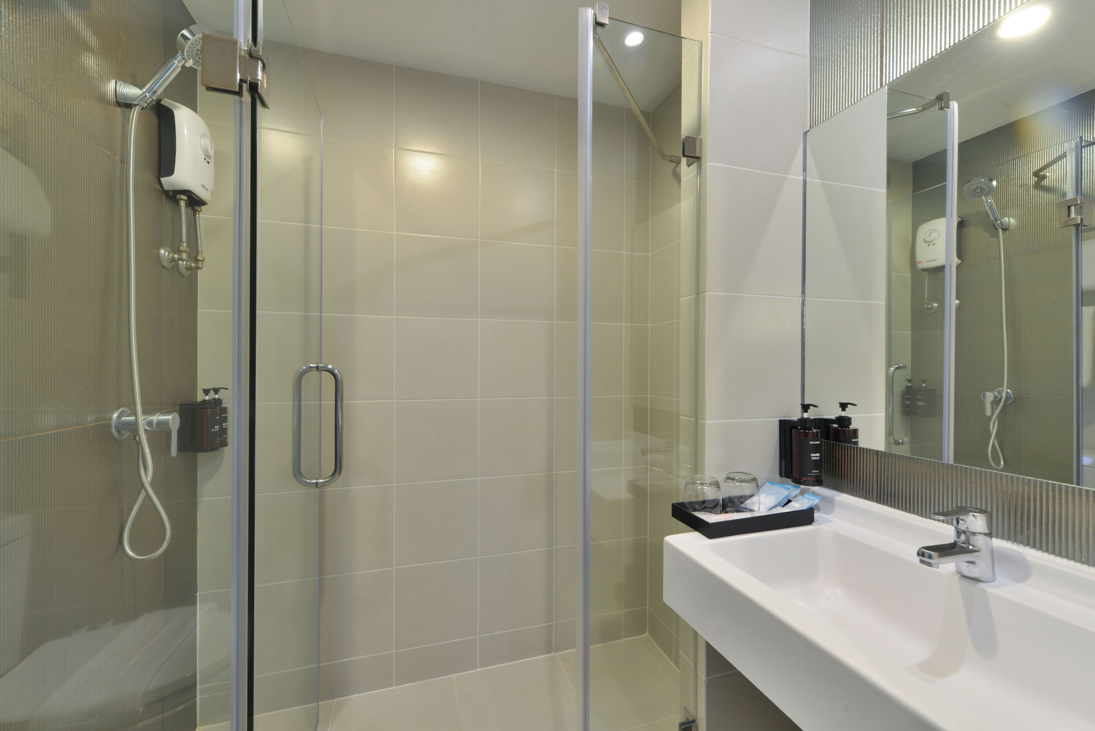 A modern bathroom with a glass-enclosed shower, a white sink, and a large mirror.