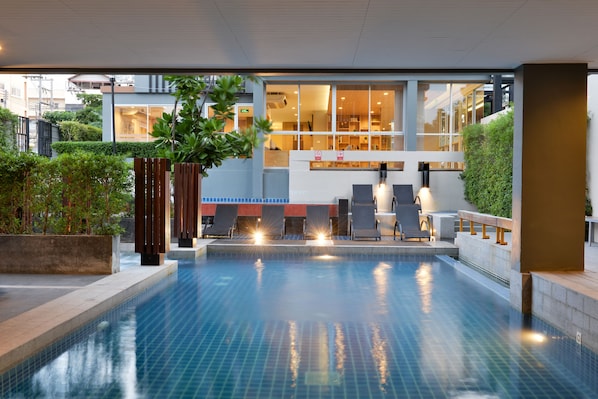 Una piscina al aire libre, sombrillas, sillones reclinables de piscina