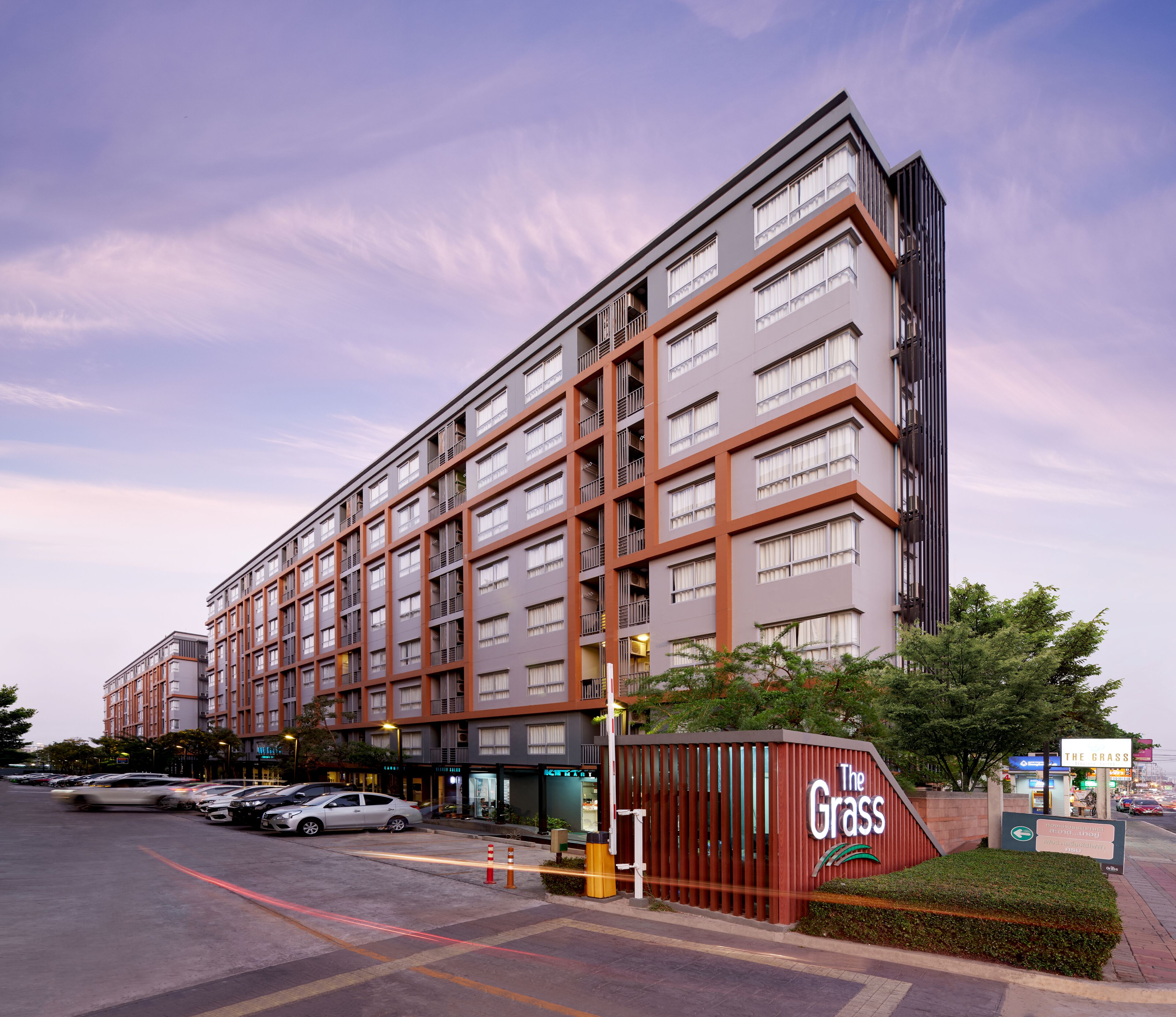 A multi-story hotel with a modern design, featuring a prominent entrance and a sign for 'The Grass'.