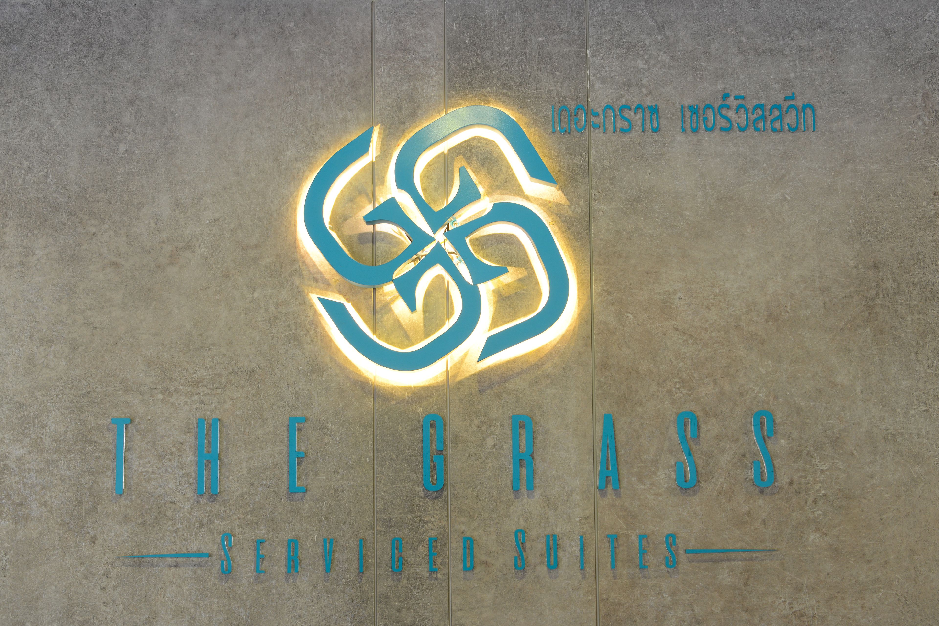 Un logotipo con letras entrelazadas y el texto 'THE GRASS' debajo.