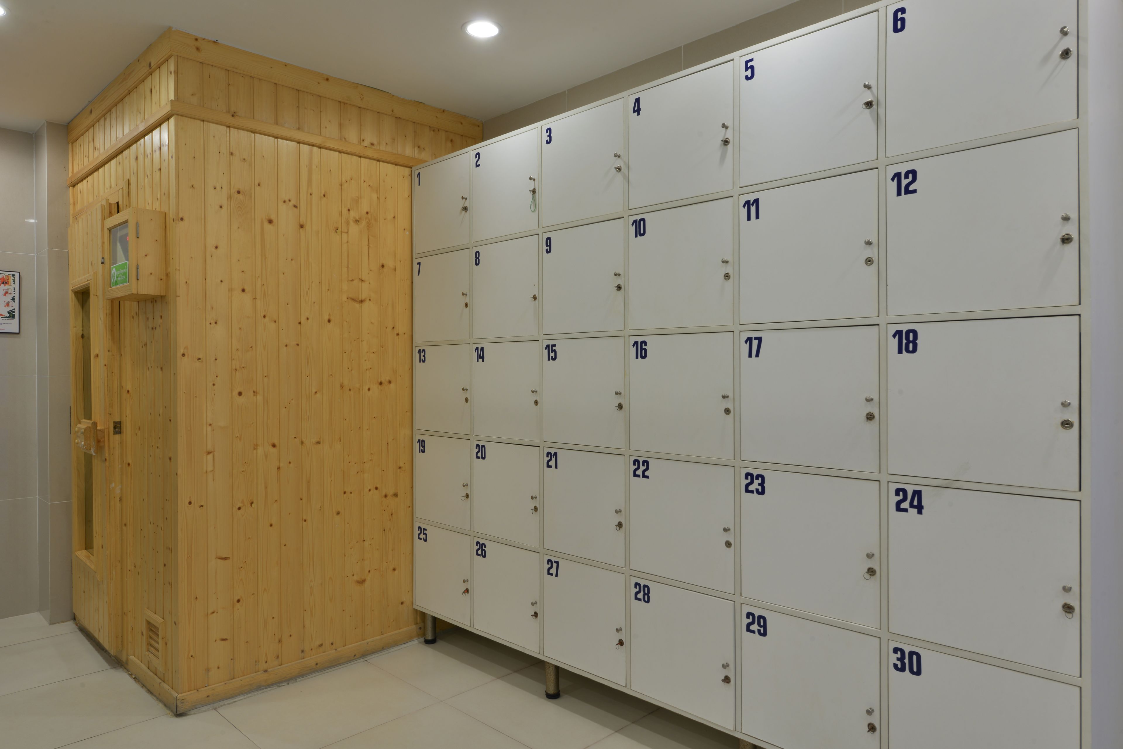 A row of numbered lockers with a wooden sauna on the left.
