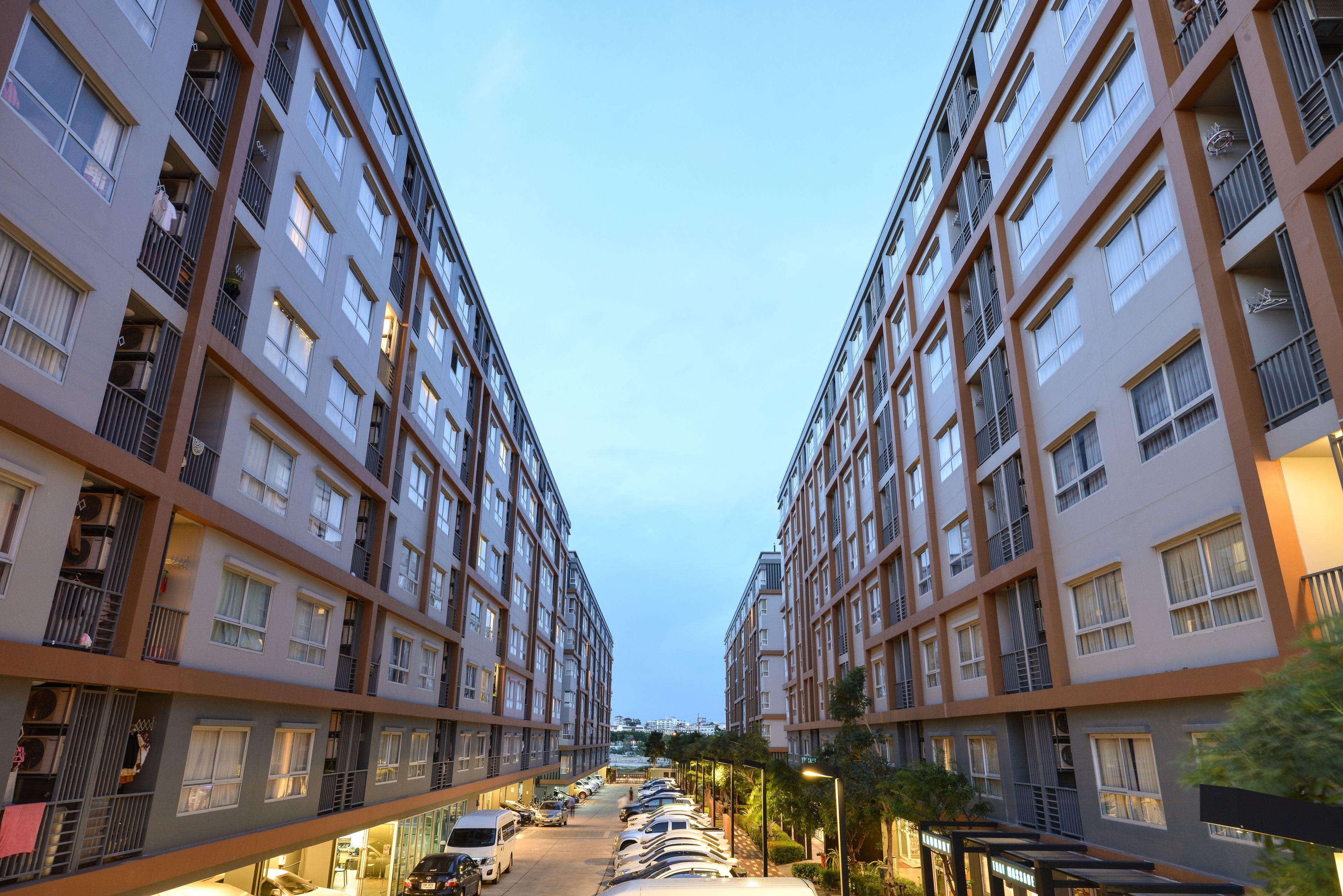 Un immeuble résidentiel à plusieurs étages, doté de balcons, d’un espace de stationnement et surplombant un ciel dégagé.