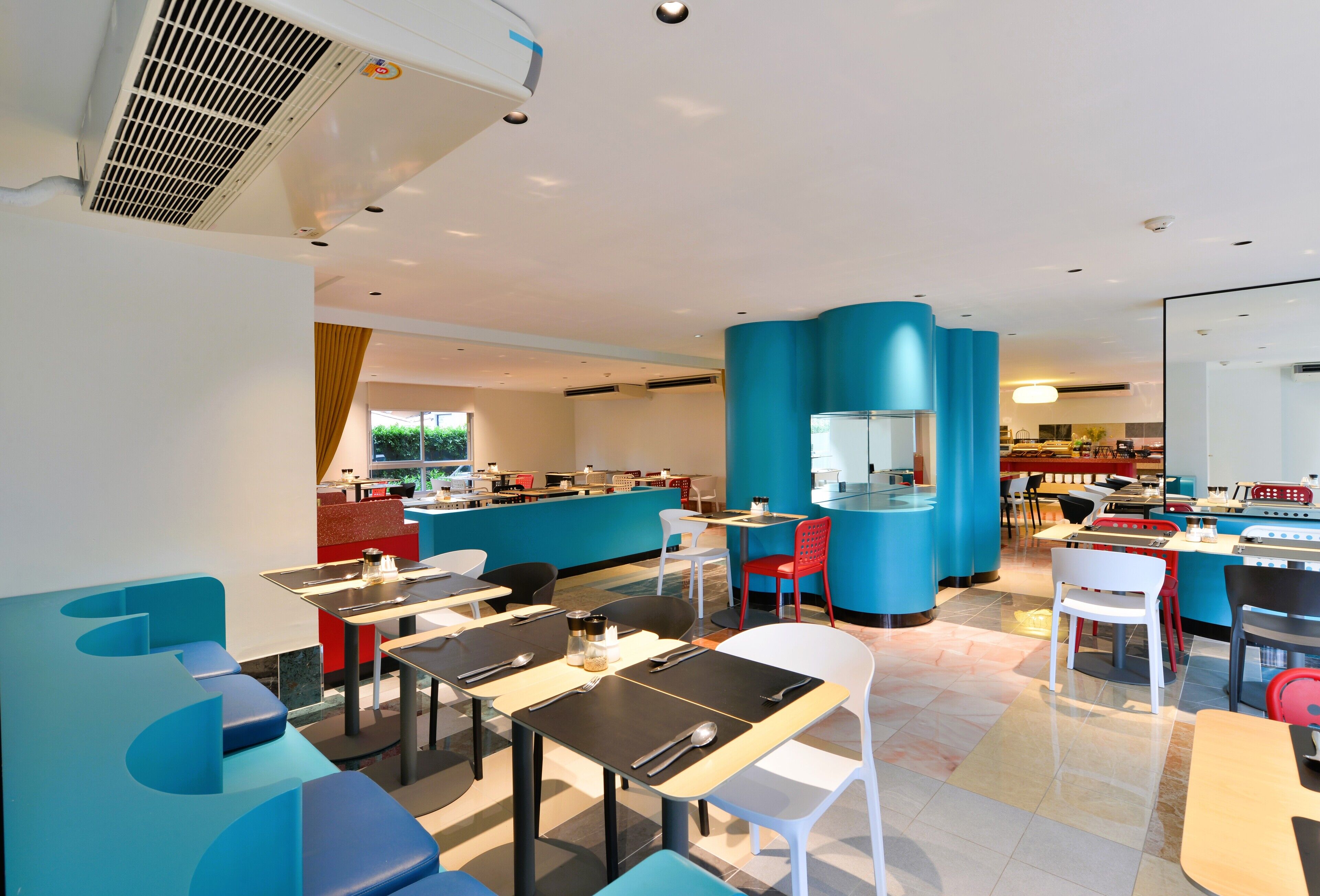 A modern restaurant with blue and white seating, a counter area, and a visible kitchen.