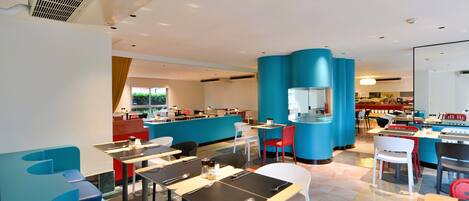 A modern restaurant with blue and white seating, a counter area, and a visible kitchen.