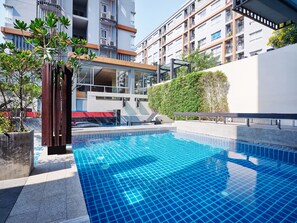 A modern hotel with a rooftop pool, outdoor seating, and a view of the cityscape. - The Grass Serviced Suites by At Mind (Pattaya)