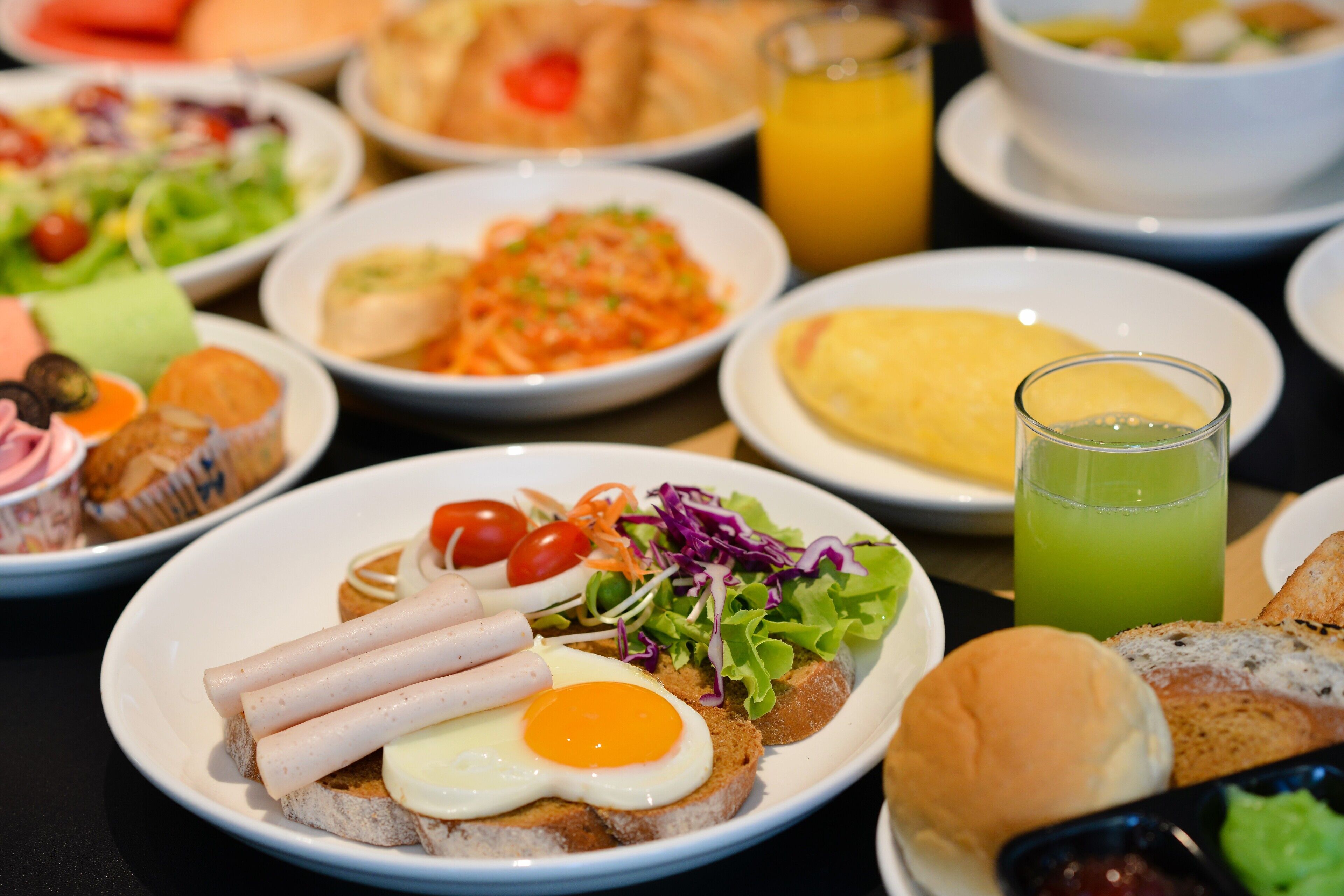 A variety of dishes including a plate with a sandwich, a bowl of salad, and a glass of juice.