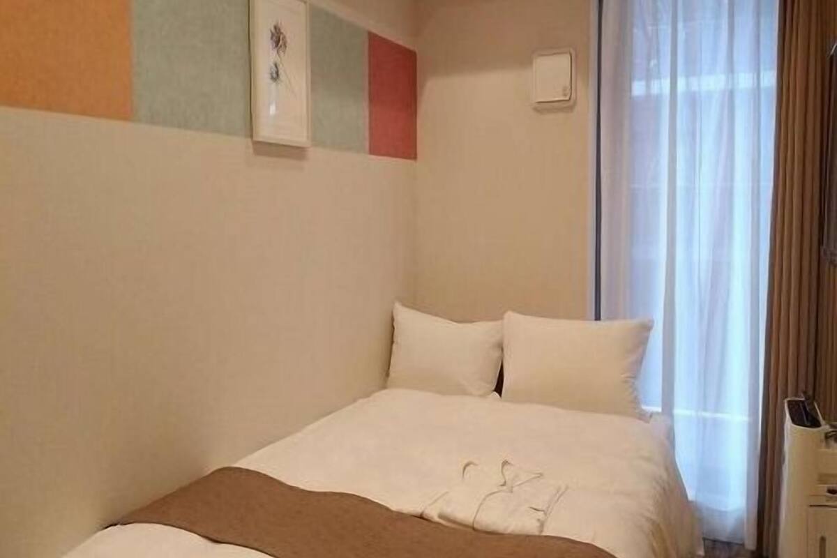 Ein Hotelzimmer mit einem Bett, einem Fenster mit Vorhängen und einer Wand mit einem Bild.