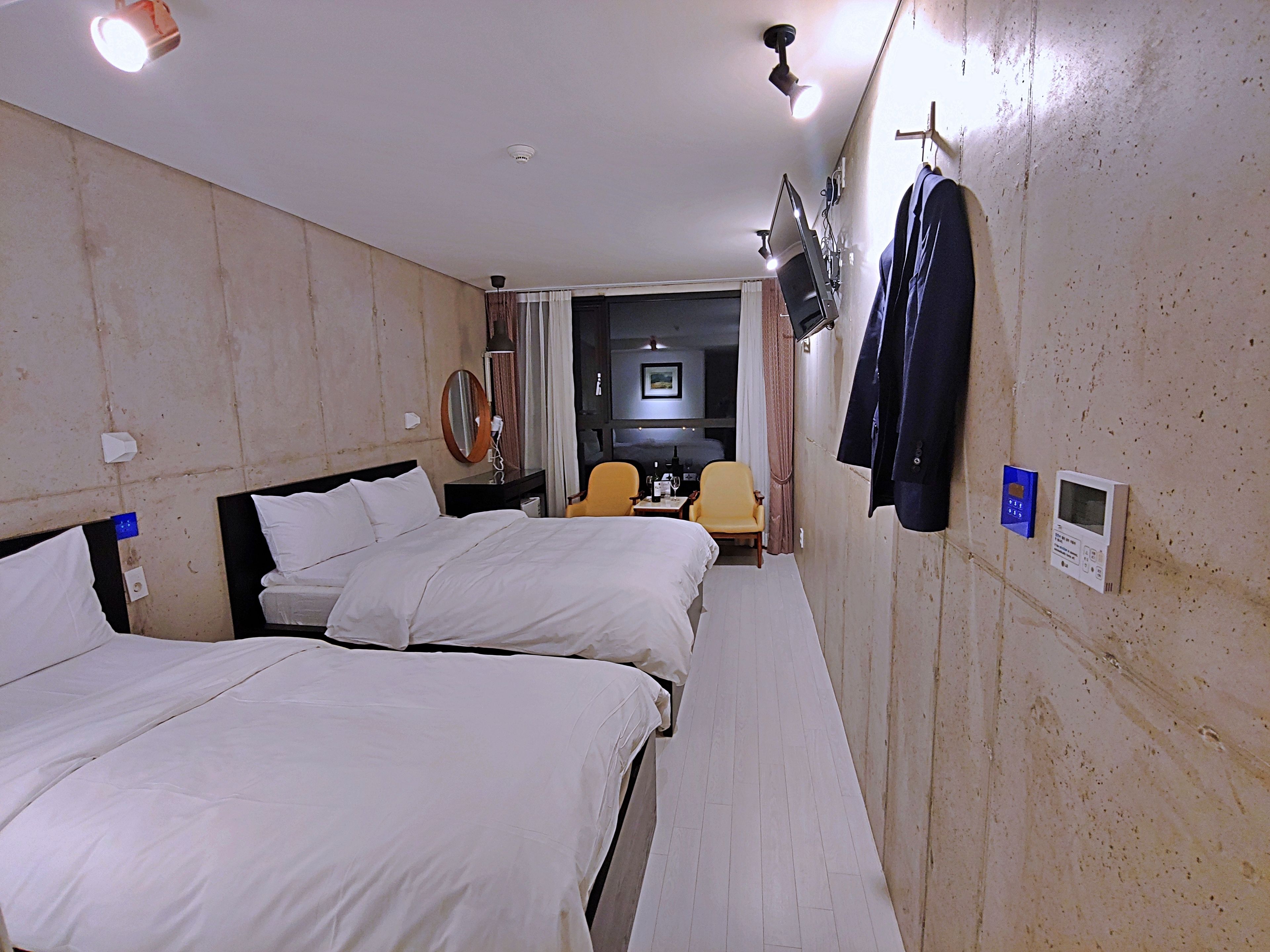 Habitació d'hotel amb dos llits, un escriptori, una cadira, un televisor i un penjallabrics.