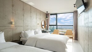 Une chambre d’hôtel avec un grand lit, un bureau, une chaise, une télévision et une vue sur la ville.