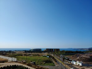 Paisatge urbà costaner amb edificis moderns, un carrer amb pas de vianants i vista al mar.