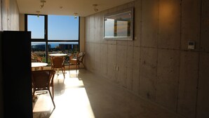 Un vaste balcon offrant une vue sur les toits de la ville, aménagé avec des fauteuils et une table en osier.