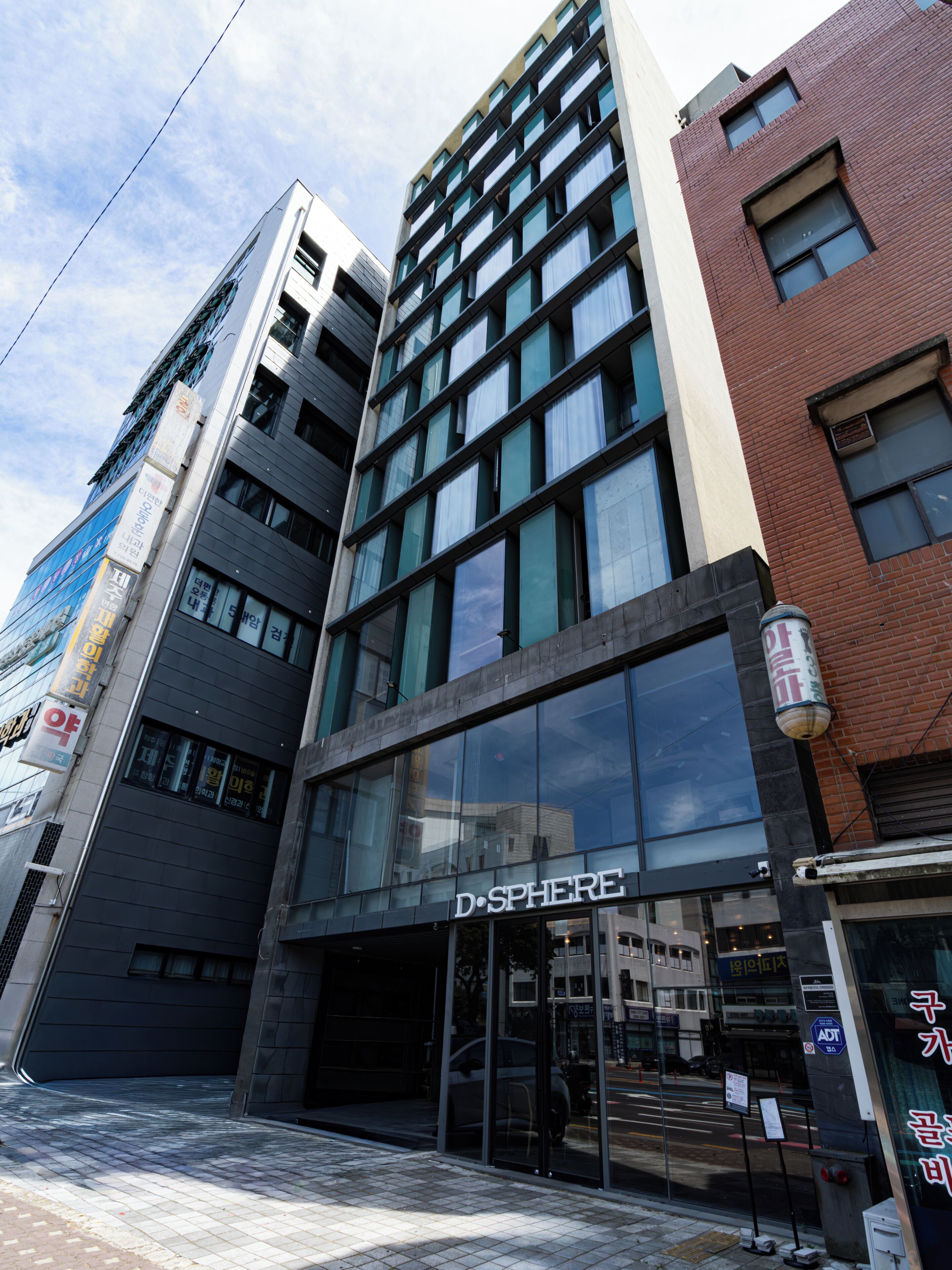 A multi-story building with a prominent glass facade, a visible entrance, and signage indicating a business establishment.