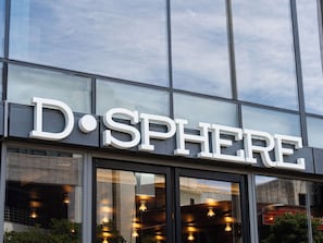 Un bâtiment doté de grandes fenêtres en verre et d’une enseigne sur laquelle on peut lire « D.SPHERE ».