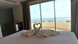 Een hotelkamer met een groot bed, een televisie en uitzicht op de zee.