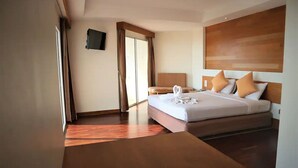 Een hotelkamer met een groot bed, een houten hoofdeinde, een flatscreen televisie aan de muur en een schuifdeur naar een balkon.