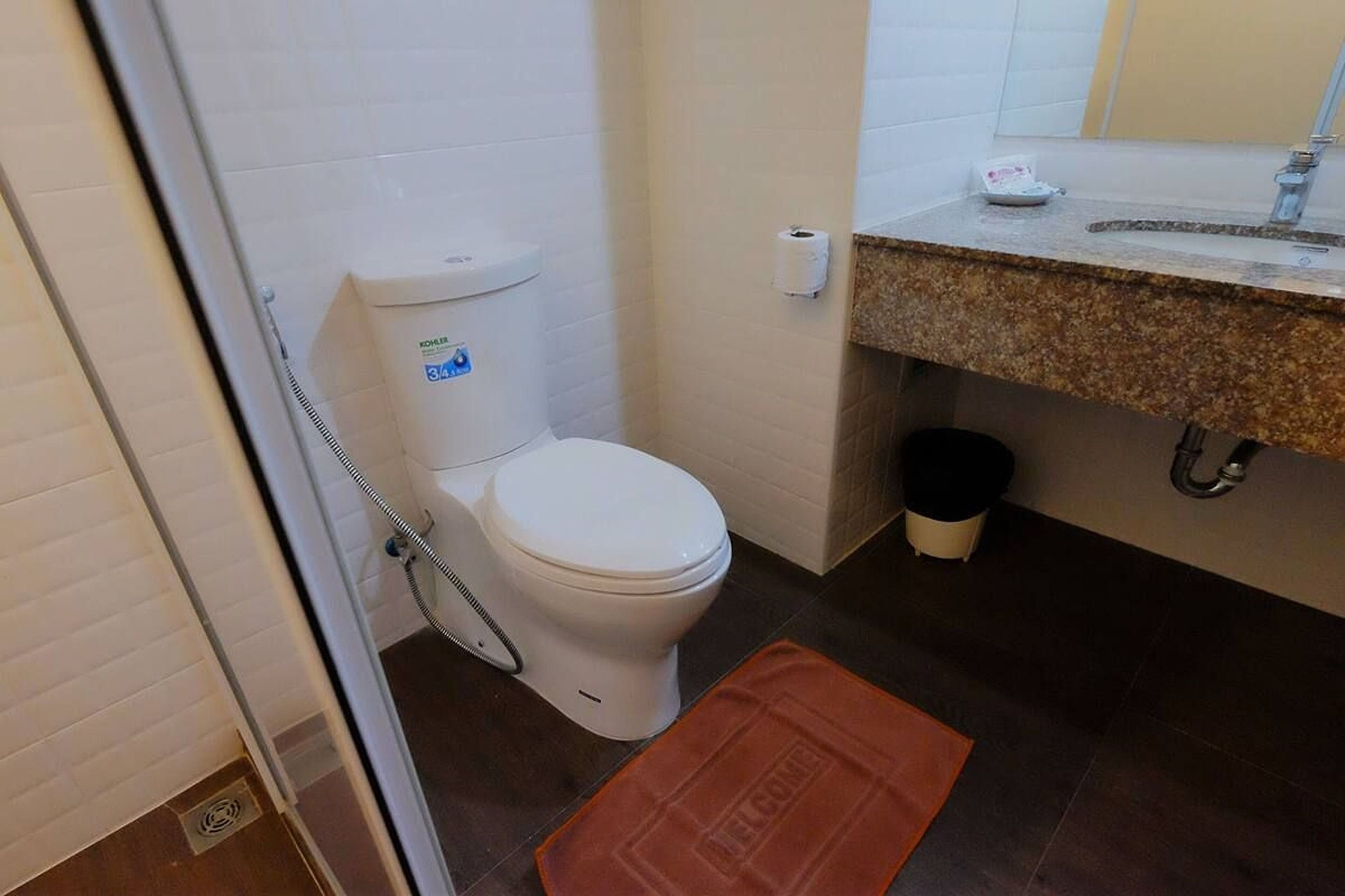 A bathroom with a toilet, a shower, and a sink.