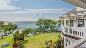 A residential property with a view of a lake, a deck with outdoor furniture, and a well-maintained lawn.