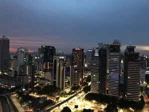 A cityscape at dusk with illuminated skyscrapers and a busy highway. - Summer Suites Vacation Home (Kuala Lumpur)