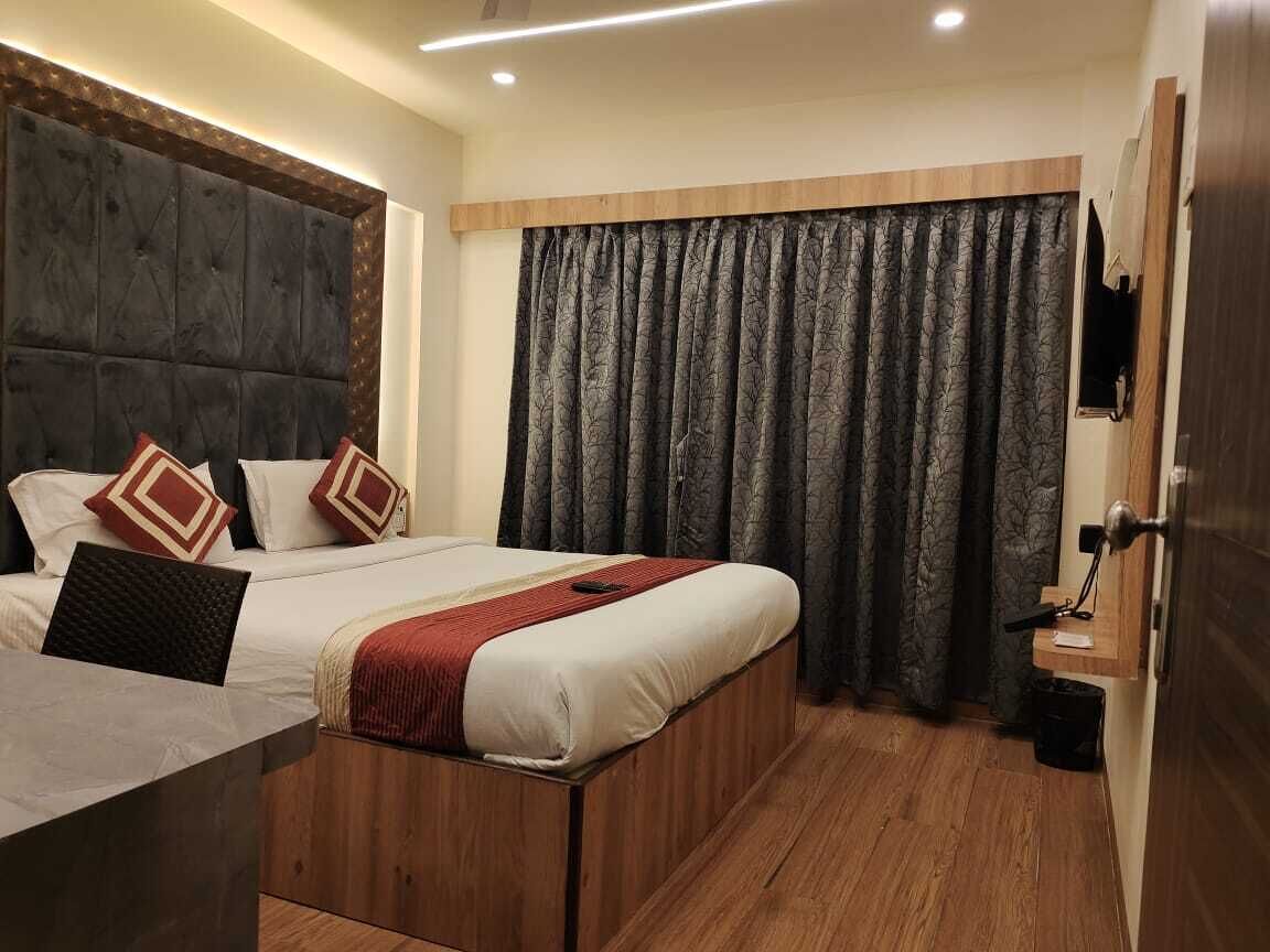 A bedroom with a large bed, a wooden headboard, and a dark curtain.
