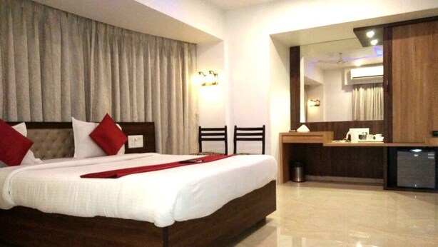 Una habitación de hotel con una cama grande, un escritorio y un espejo.