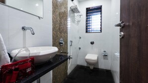 Un baño con lavamanos blanco, inodoro y zona de ducha.