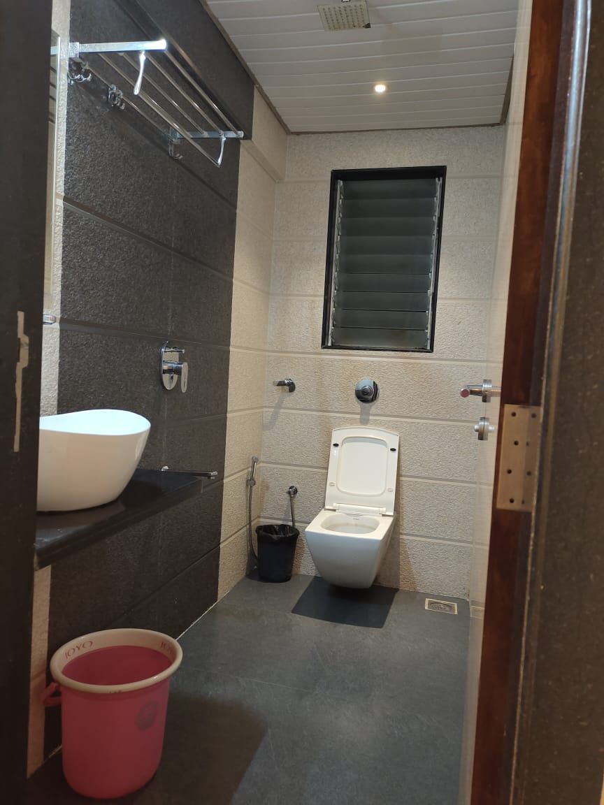 Un baño pequeño con inodoro y lavamanos blancos, y una zona de ducha.