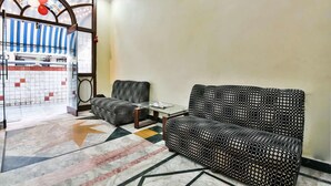 Un vestíbulo de hotel con un sofá estampado, una mesita pequeña y un arco decorativo.