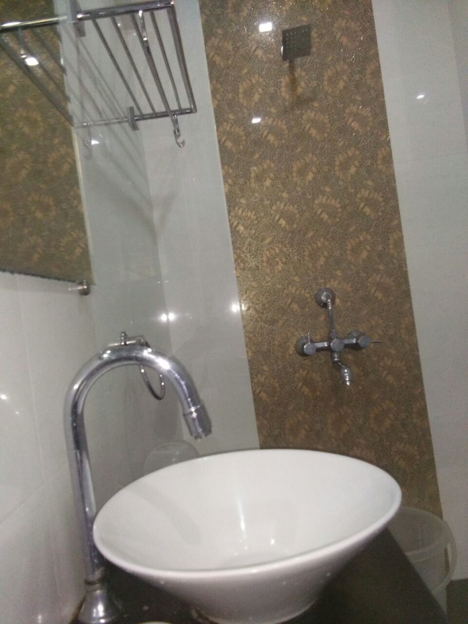 A bathroom with a white sink, a chrome faucet, and a shower head.