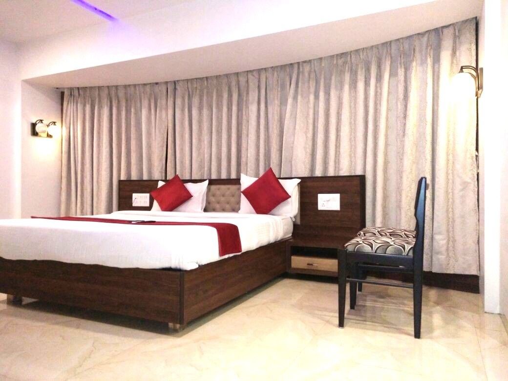 Habitación de hotel con una cama grande, una silla y una ventana con cortinas.
