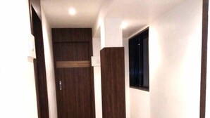 Un pasillo con suelo de baldosas, paneles de madera en las paredes y una ventana a la derecha.