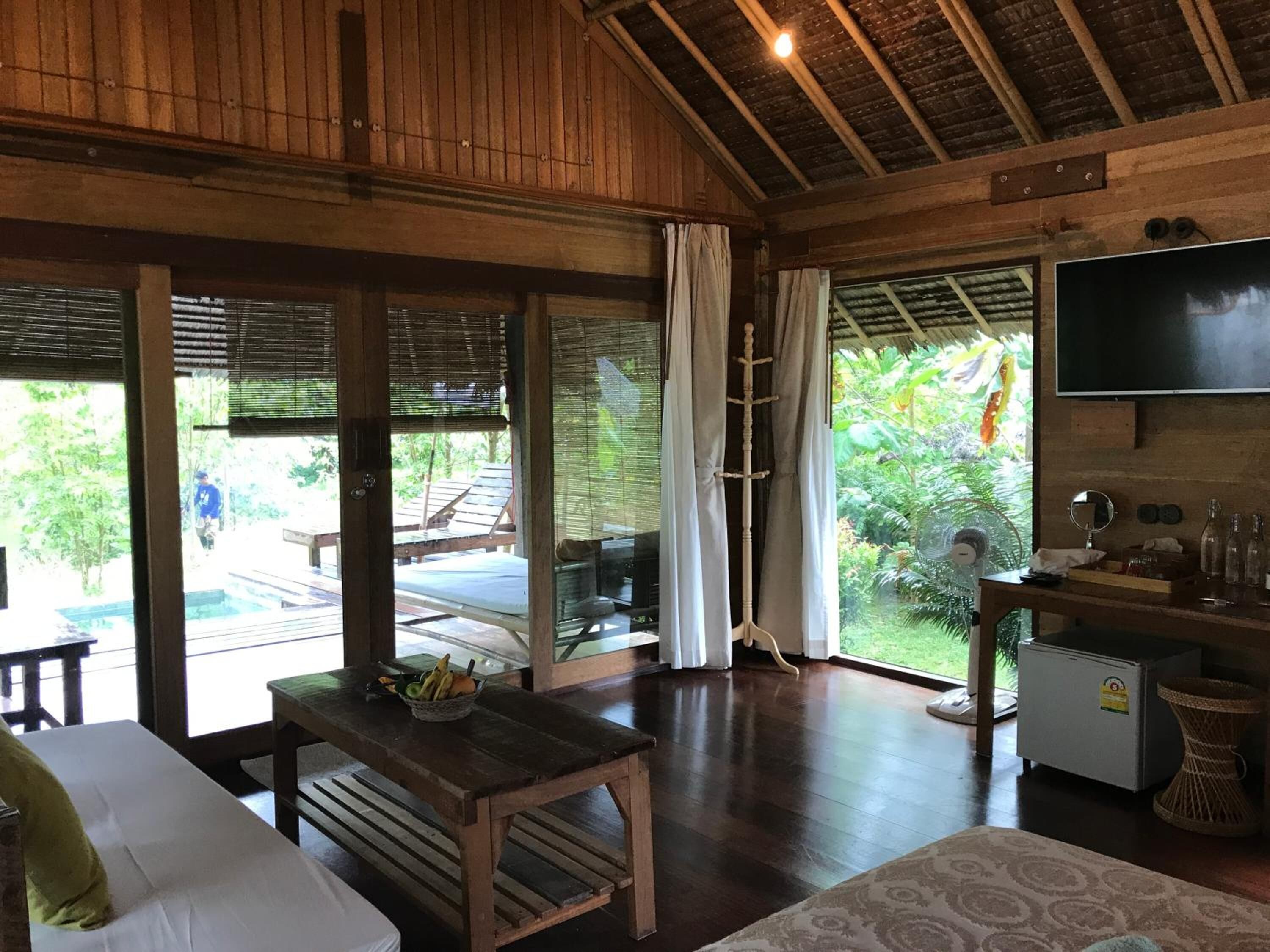 A wooden interior with a TV, a small kitchen area, and a view of the outdoors.