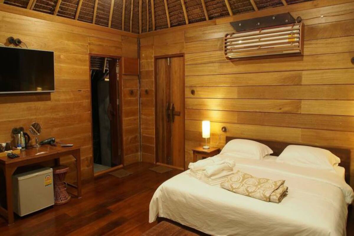 A wooden room with a bed, a desk, a TV, and a heater.