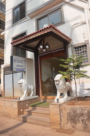 A hotel entrance with a reception desk, two lion statues, and a small palm tree. - Hotel Calangute Central (Calangute)