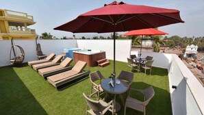Eine Dachterrasse mit Liegestühlen, einem Whirlpool und einem Tisch mit Stühlen.