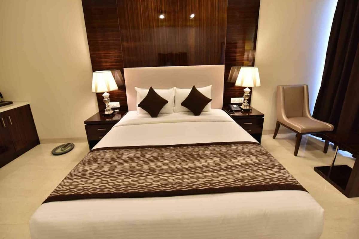 Habitación de hotel con una cama grande, dos mesitas de noche con lámparas, una silla y un armario.