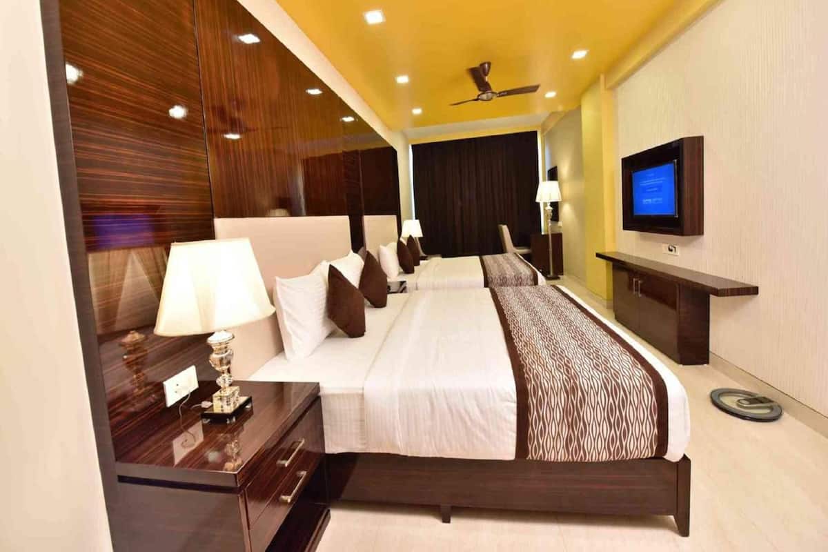 Una habitación de hotel con una cama grande, televisión, escritorio y ventilador de techo.