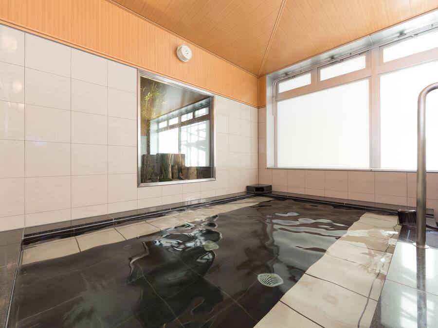 Una piscina interior moderna con vista despejada del cielo a través de amplios ventanales, techo de madera y paredes con azulejos.