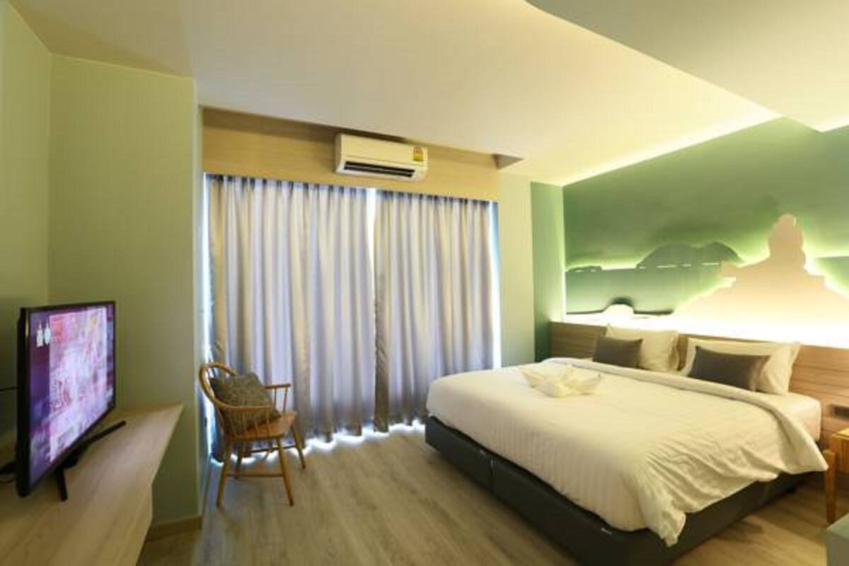 A hotel room with a bed, a television, a chair, and a large window with curtains.