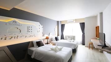 Ett hotellrum med två sängar, ett skrivbord med en tv och en dekorativ väggdekoration.