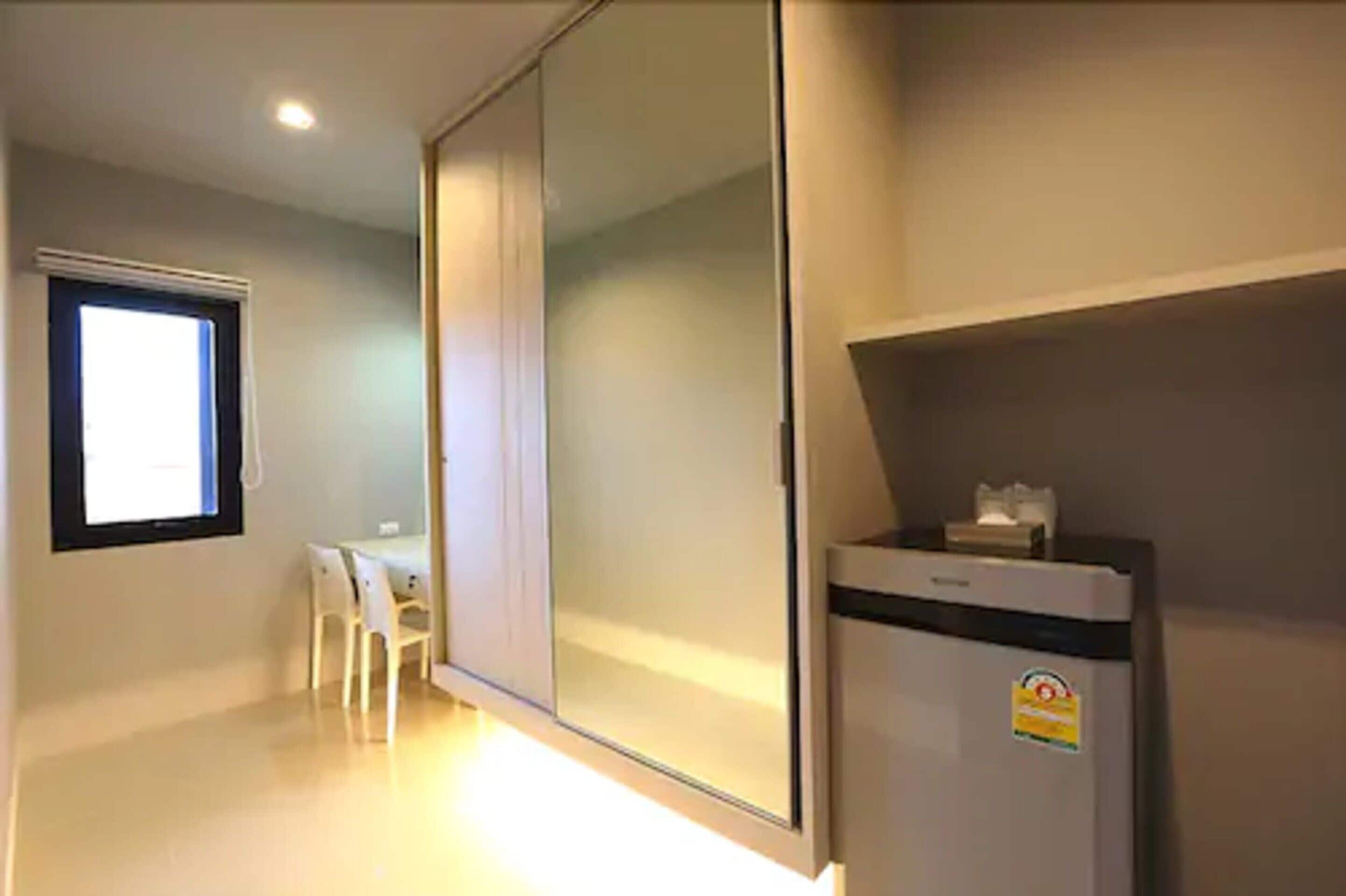 A room with a sliding door, a small table with chairs, a refrigerator, and a window.