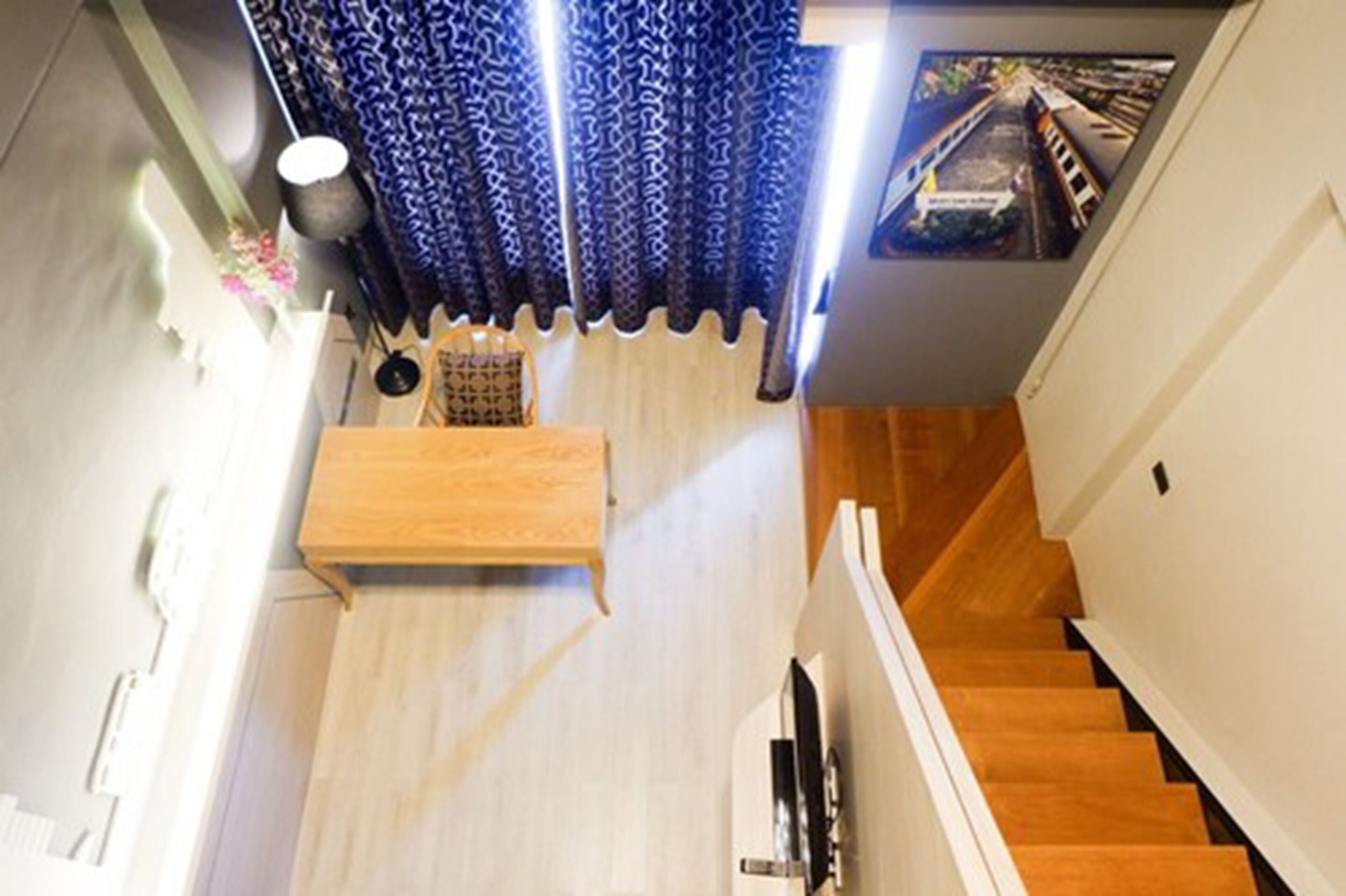 A staircase leading to a second floor with a wooden floor and a blue patterned curtain.
