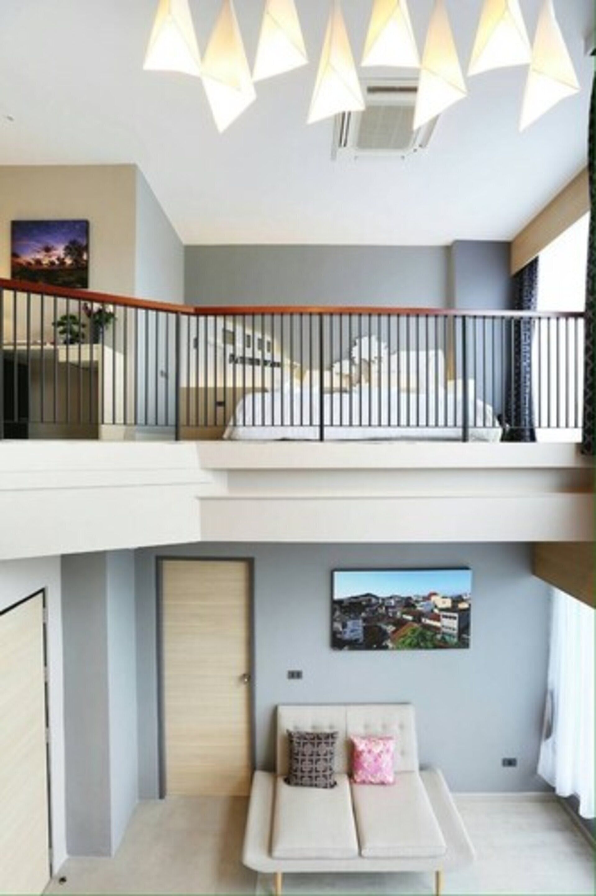 Ein modernes Wohnzimmer mit einer Sofagarnitur, einem Gemälde an der Wand und einem Balkon mit Geländer.