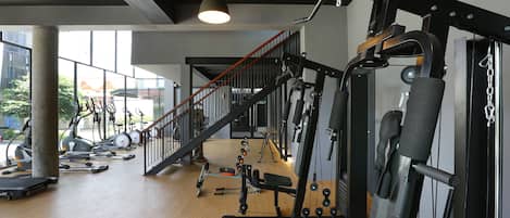 A gym with various exercise equipment, a staircase, and large windows.