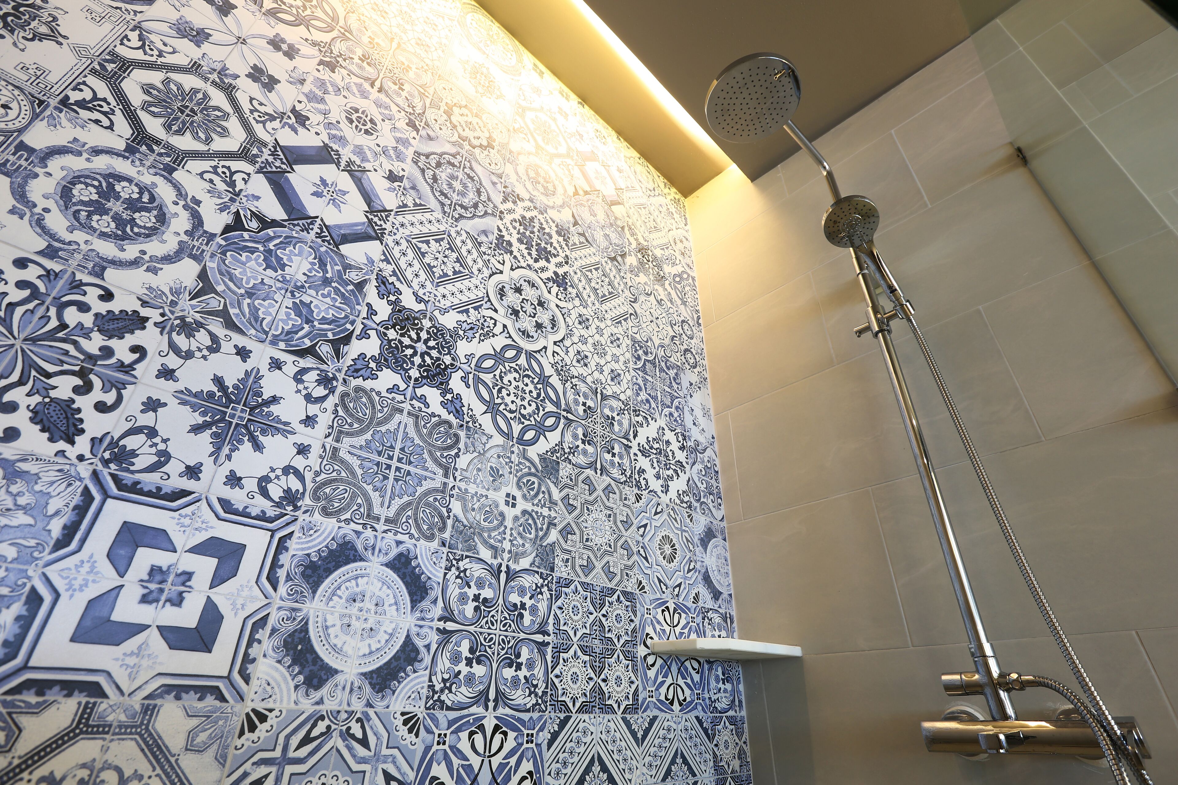 A bathroom with intricate blue and white tile patterns and a modern shower fixture.