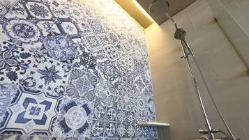 A bathroom with intricate blue and white tile patterns and a modern shower fixture.