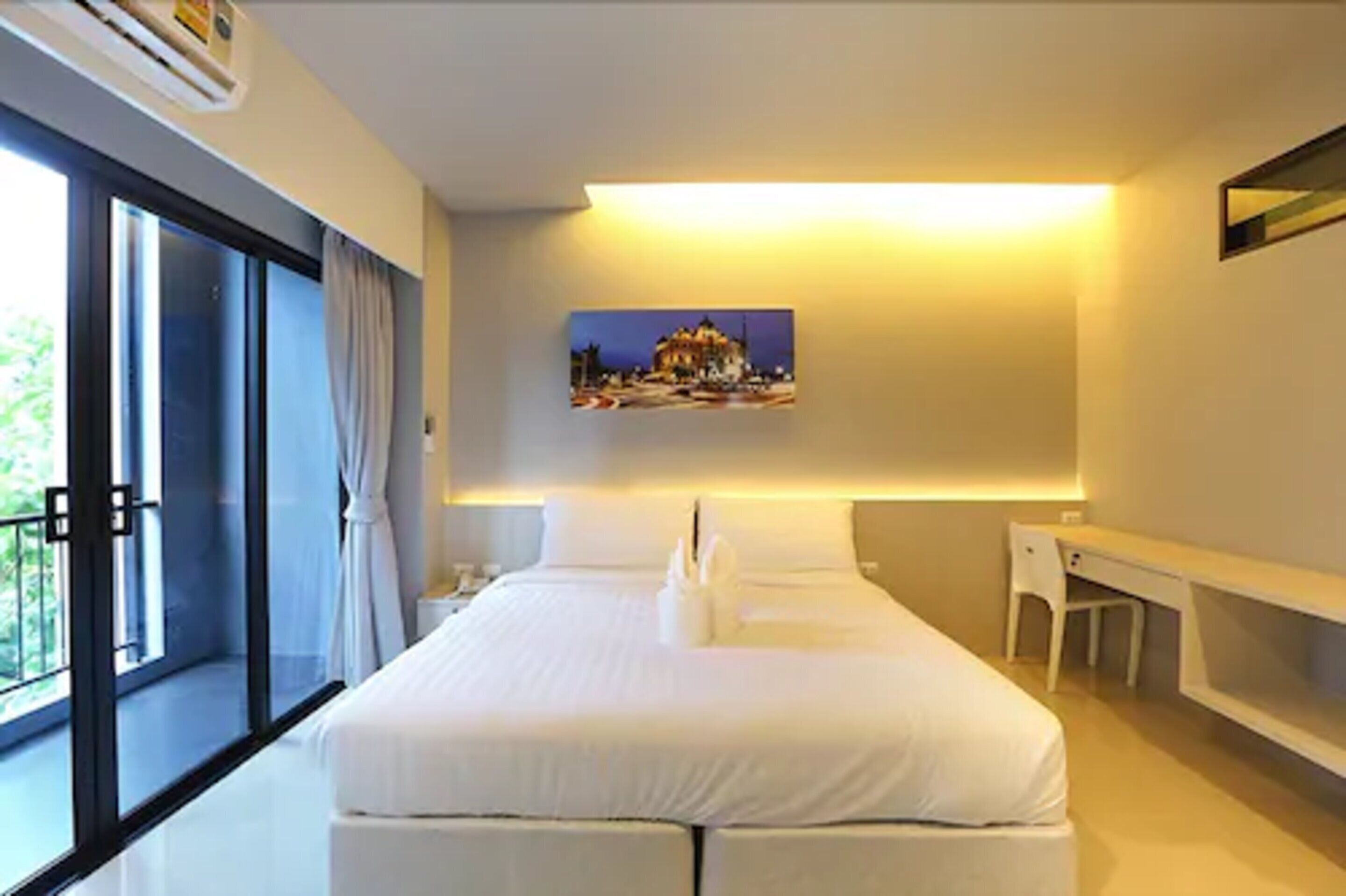 Une chambre d’hôtel moderne avec un grand lit, un bureau et un tableau au mur.