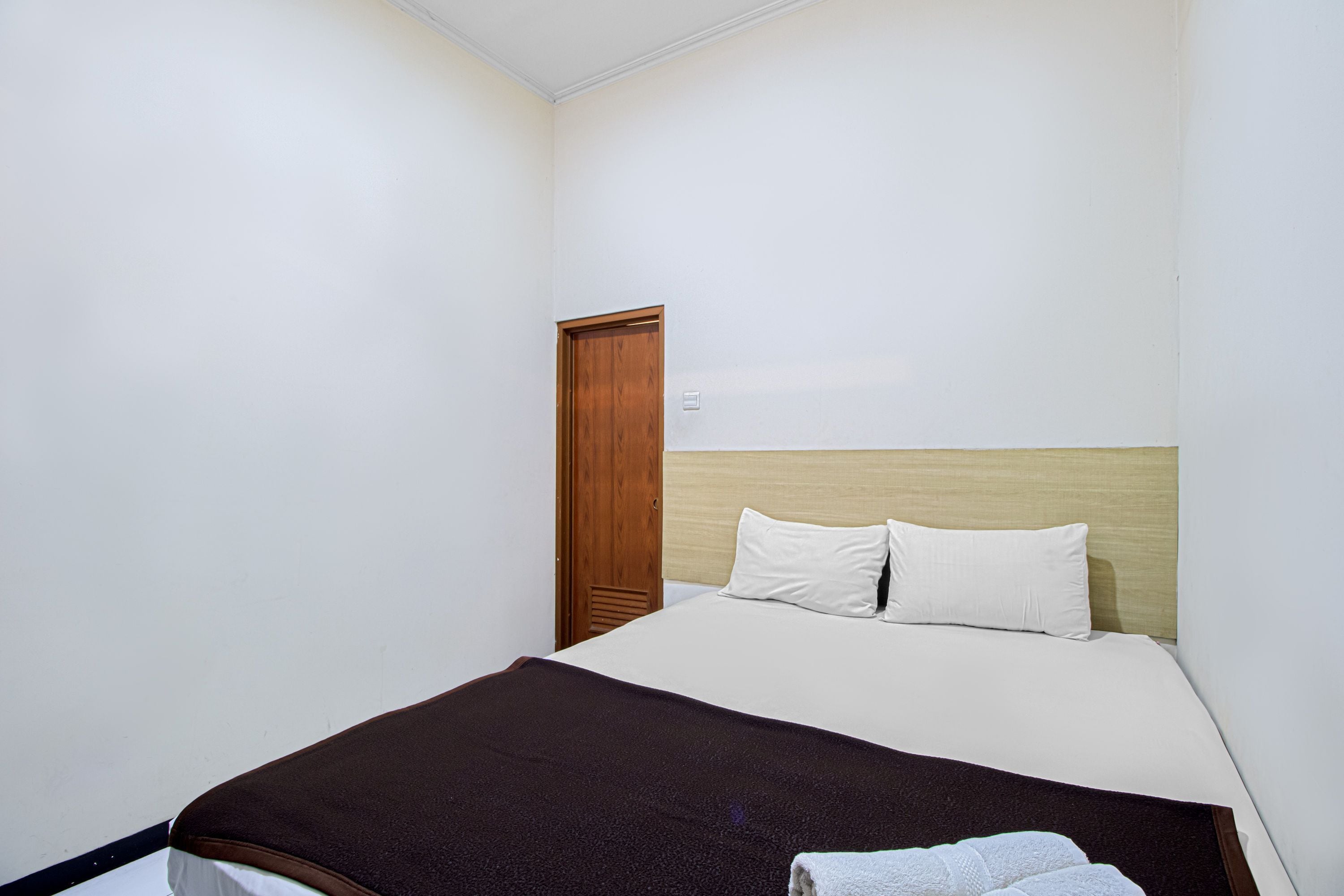 Une chambre à coucher avec un lit, une porte en bois et un mur blanc.